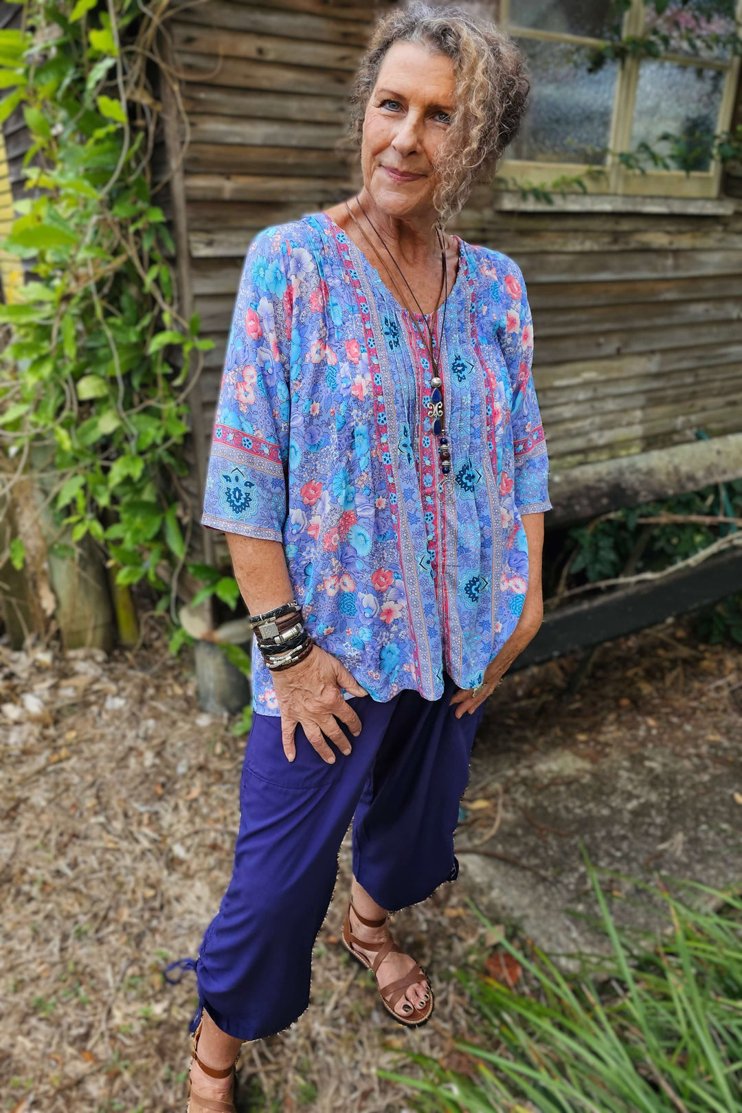Woman wearing a light rayon purple blouse and navy pants standing outdoors.