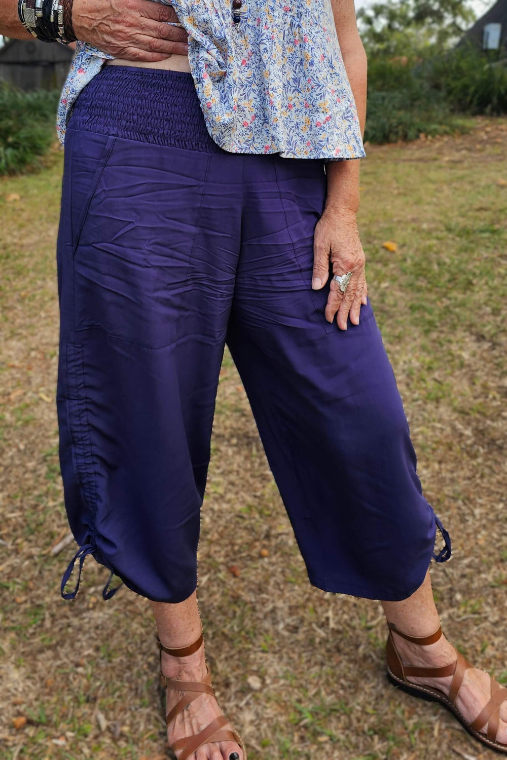 Person wearing navy pants and a floral shirt standing on grass