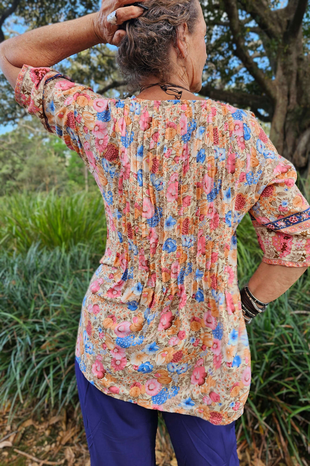Person wearing a colorful floral blouse with a natural background