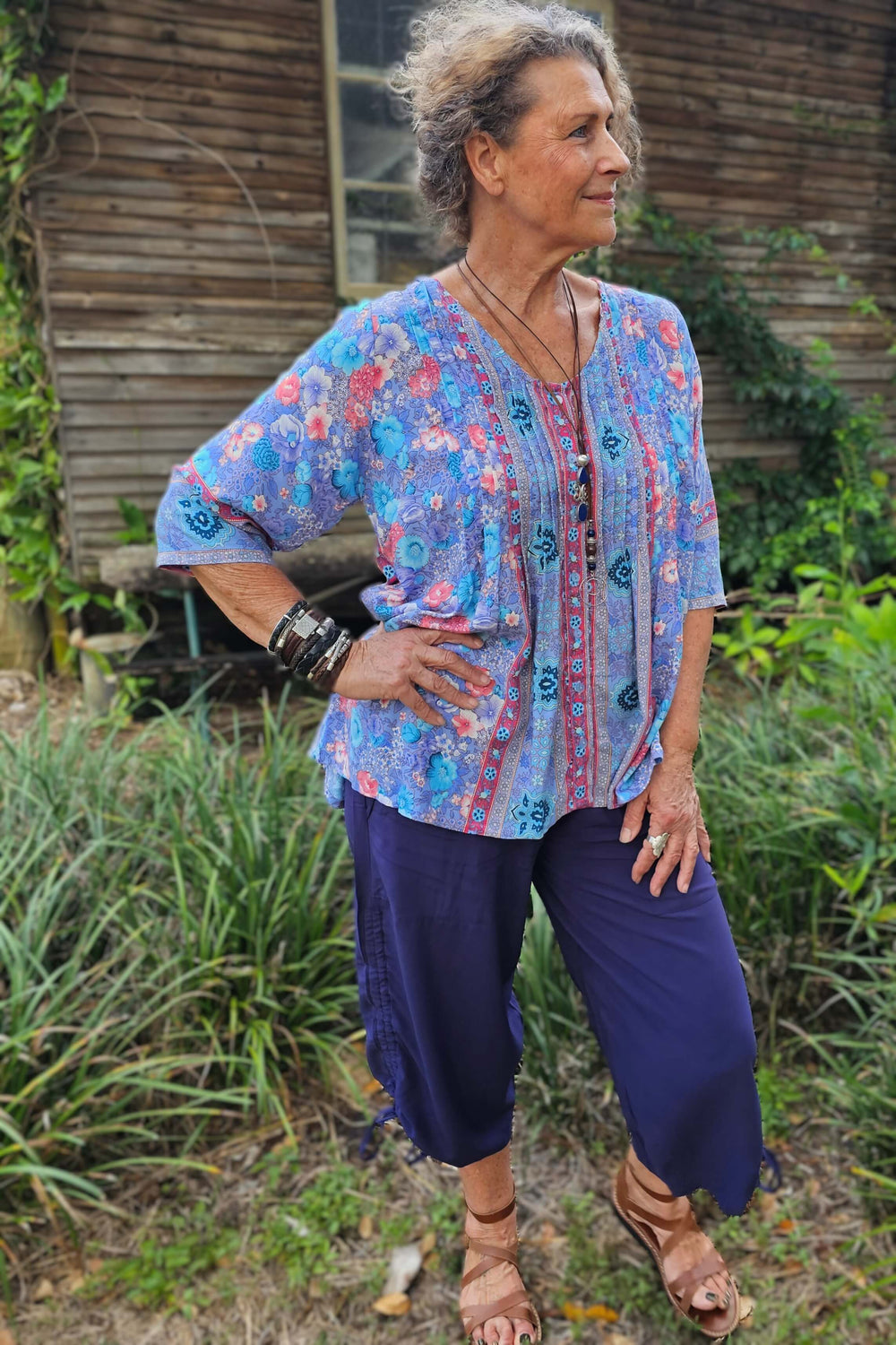 Woman wearing a purple feature tunic with 3/4 sleeve and navy pants.