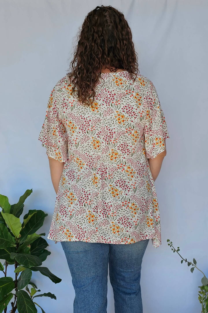 Back view of white V-neck blouse with shirred waist and flutter sleeves